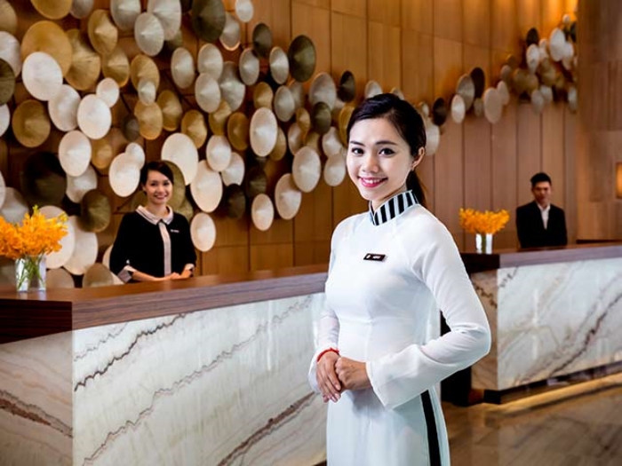 Lễ tân khách sạn hỗ trợ khách tại quầy tiếp tân